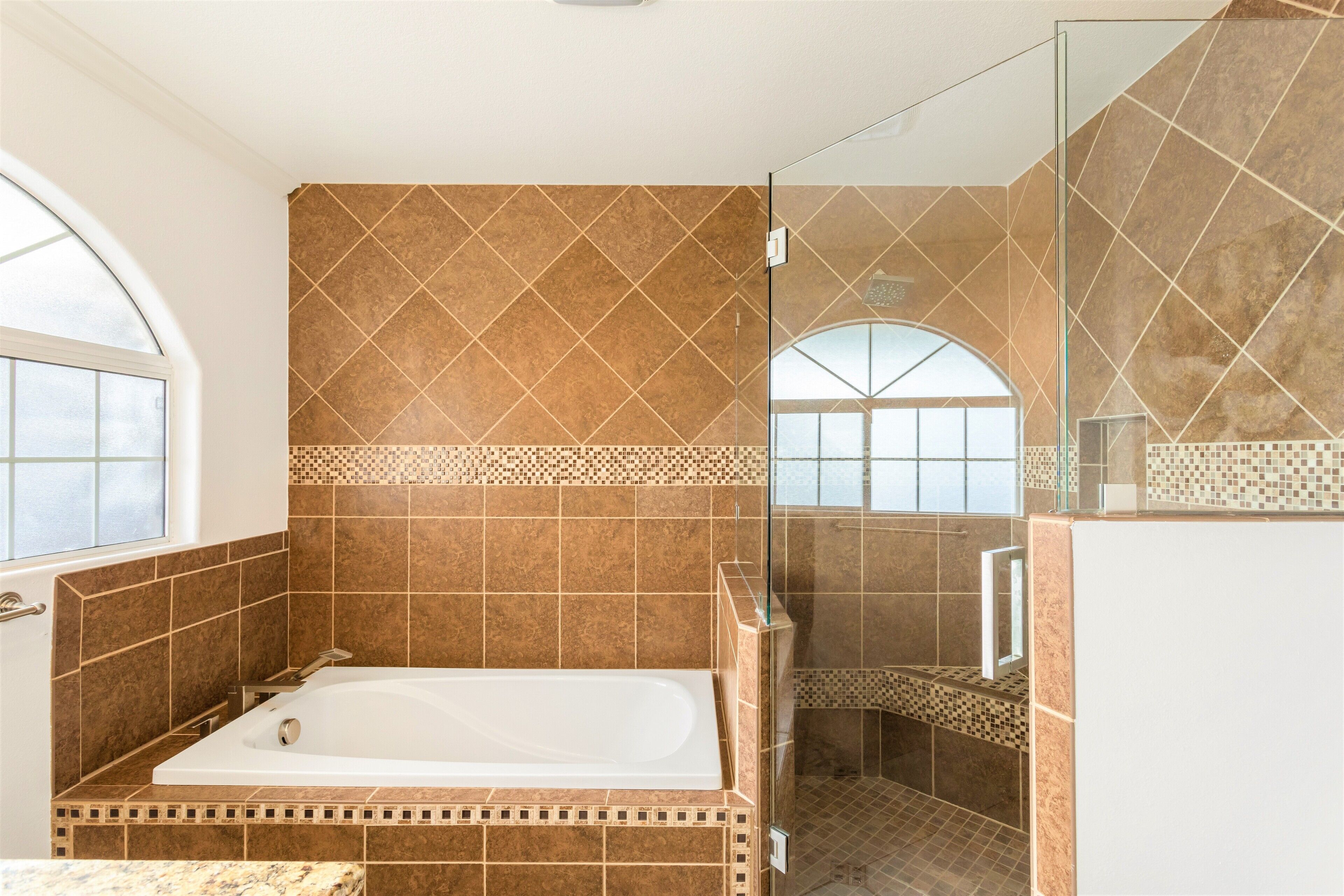 A bathroom with a large bathtub, a shower area, and a glass-enclosed shower stall.