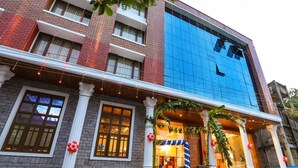 Un hotel con fachada de ladrillo, un edificio de vidrio azul y una entrada decorada con escalones y barandillas.