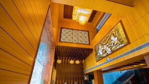 Un vestíbulo con paneles de madera, una recepción, una escalera y un gran elemento decorativo en la pared.
