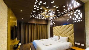 Una habitación de hotel moderna con una cama grande, un televisor de pantalla plana y un techo con diseños geométricos.