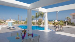 A rooftop terrace with a pool, outdoor seating, and a view of the sea.