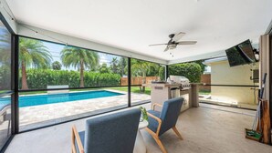 Une terrasse extérieure moderne dotée d’une piscine, d’un espace barbecue et d’un coin salon.