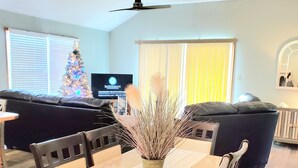 Un comedor con una mesa, sillas, un árbol de Navidad y un ventilador de techo.