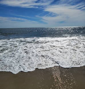 Une plage où les vagues se brisent sur le rivage sous un ciel dégagé.
