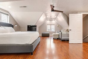Ein Schlafzimmer mit Bett, Deckenventilator, Fernseher, Fenster und Tür.