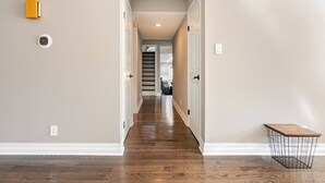 Un couloir doté d’un plancher en bois, de murs blancs et d’un banc à la structure en fil de fer.