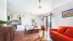 A spacious living area with a red sofa, a dining table set for four, and a kitchen in the background. - Il Gelsomino, apartment between Tuscany and Umbria (Villastrada)