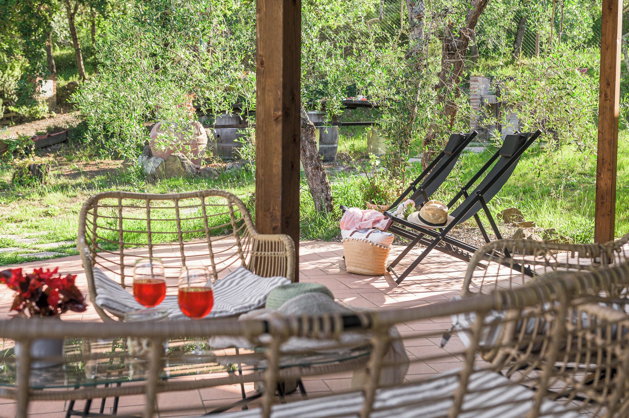 Un espace extérieur aménagé avec des meubles en osier, un panier et deux verres à vin.