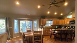 A spacious kitchen with wooden cabinets, a dining area with a table and chairs, and a ceiling fan. - Home in the Pines • Bathroom for Every Bedroom (Flagstaff)
