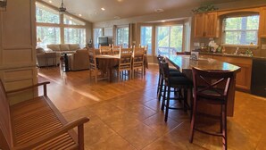 A spacious kitchen with a dining area, large windows, and a ceiling fan. - Home in the Pines • Bathroom for Every Bedroom (Flagstaff)
