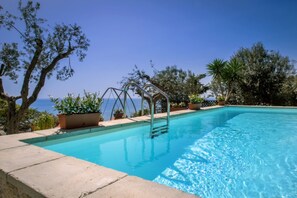 Una piscina rectangular con agua cristalina, rodeada por una solana de piedra.