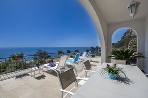 A terrace with white chairs and a table, overlooking a coastal view with the sea and a mountain in the background. - VILLA SOLANGE, PRIVATE POOL NEAR SORRENTO (Nerano)