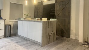 Una cocina moderna con una isla central, armarios blancos, una pared de acento de madera e iluminación colgante.