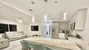 Una cocina moderna con una isla de mármol, taburetes de bar y electrodomésticos de acero inoxidable.