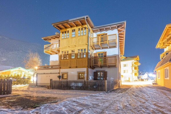 A multi-story building with balconies, a wooden fence, and a snow-covered ground.