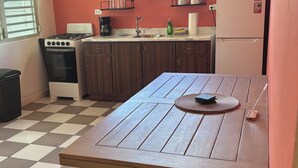 Cozinha com piso xadrez, mesa de madeira e armários.