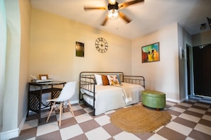 A bedroom with a bed, desk, chair, and a ceiling fan.