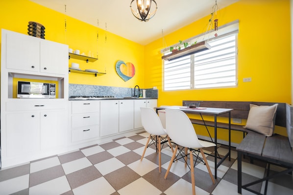 A kitchen with white cabinets, a microwave, and a checkered floor.