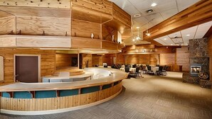 Eine moderne Hotelhalle mit einer gebogenen Rezeption, Holzvertäfelung und einem Steinkamin.