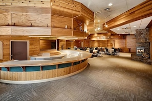 Eine moderne Hotelhalle mit einer gebogenen Rezeption, Holzvertäfelung und einem Steinkamin.