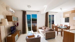 En moderne stue med sofa, fjernsyn og spiseplads.