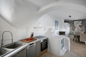 Une cuisine moderne équipée d’un four encastré, d’un évier et d’une planche à découper en bois sur laquelle se trouvent des tomates.