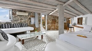 Un salón moderno de planta abierta con paredes de piedra, suelo de baldosas de piedra y un ventanal grande.