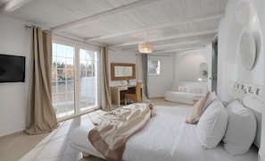 Une chambre comprenant un lit, un bureau, une chaise, un téléviseur et une salle de bain avec des toilettes et une douche.