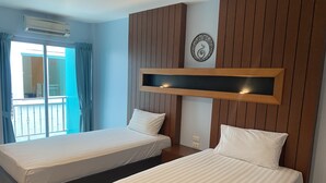A hotel room with two beds, a large window with curtains, a wall-mounted air conditioner, and a decorative wall piece. - Cocoon Deva Hotel (Patong)