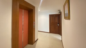 A hallway with two wooden doors, one with a red frame and the other with a brown frame, leading to different rooms. - Cocoon Deva Hotel (Patong)