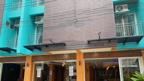 A hotel with a modern design, featuring a large glass entrance, outdoor seating area, and a visible air conditioning unit. - Cocoon Deva Hotel (Patong)