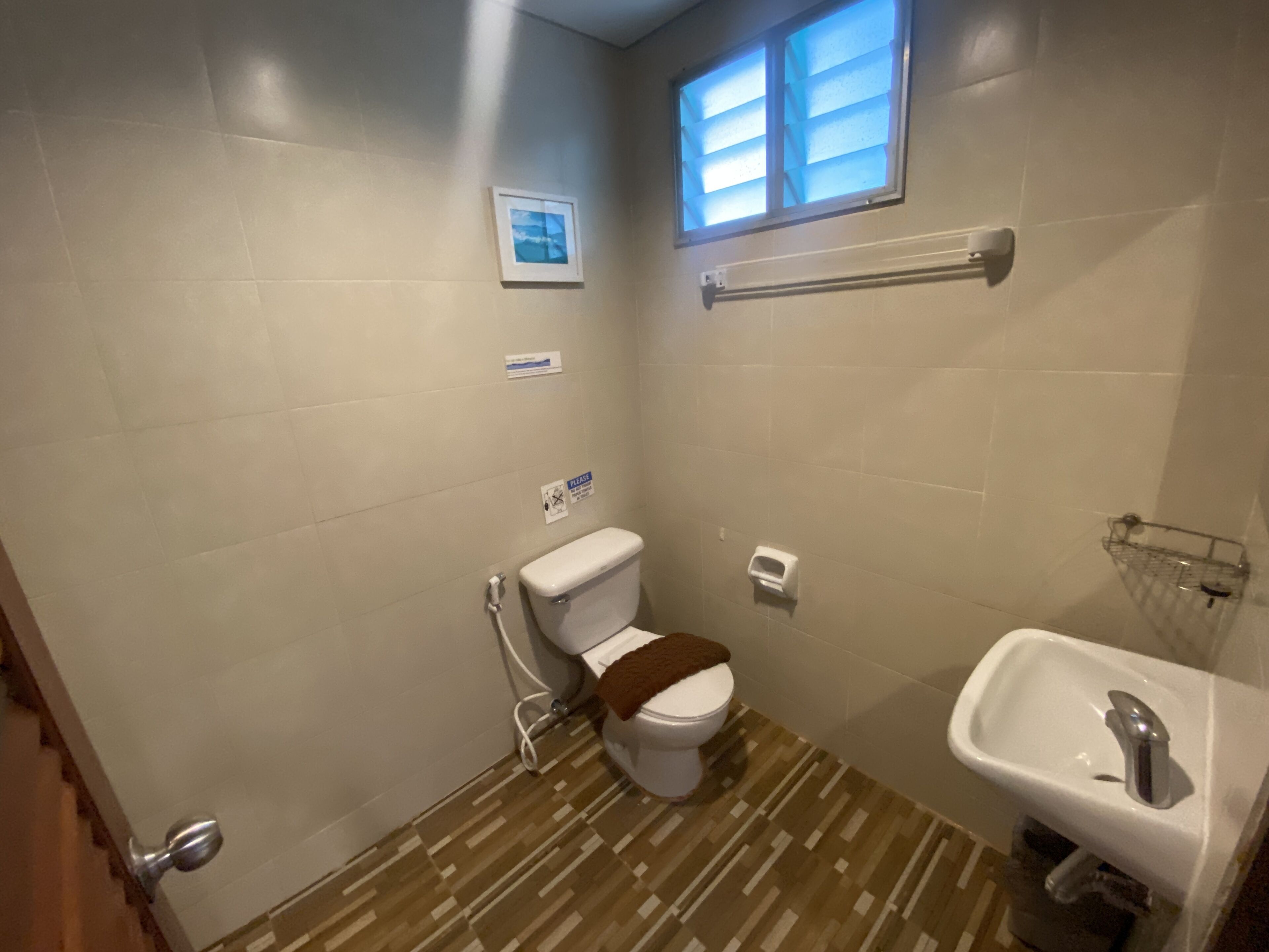 A small bathroom with a toilet, a sink, and a window.