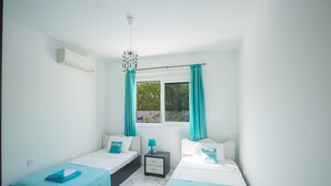 Une chambre d’hôtel avec deux lits, une fenêtre avec des rideaux, une table de chevet et un appareil de climatisation.