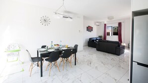 Un salon moderne avec un coin repas, comprenant un canapé noir, une table à manger avec des chaises et une chaise haute pour bébé.