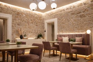 A room with a stone wall, a sofa, a dining table, and chairs. - Martina Suites (Rome)