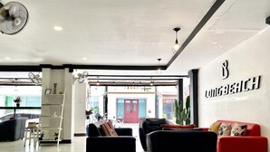 A modern hotel lobby with a reception desk, seating area with sofas, and a visible outdoor entrance. - Beachwalk Patong (Patong)