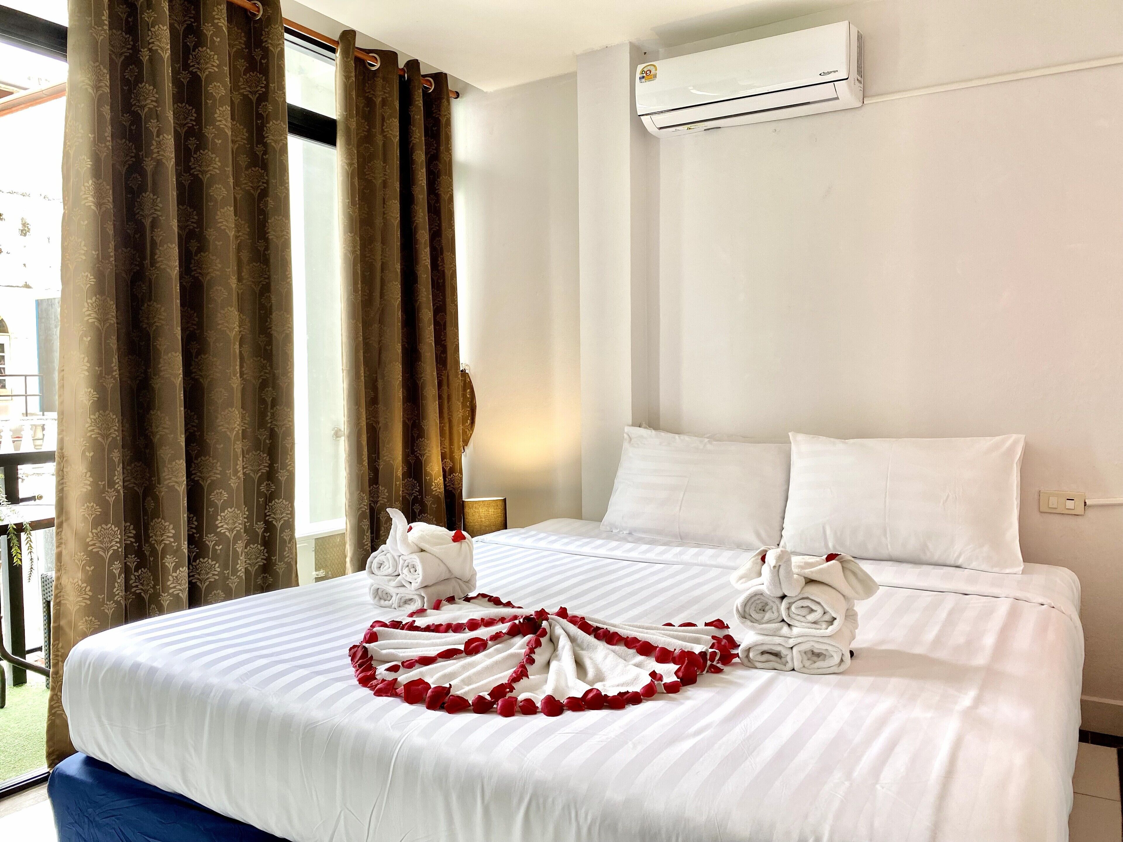 Quarto de hotel com cama, roupa de cama branca, janela com cortinas, ar condicionado e vista para o exterior.