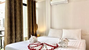 A hotel room with a bed, white bedding, a window with curtains, an air conditioning unit, and a view of the outside. - Beachwalk Patong (Patong)