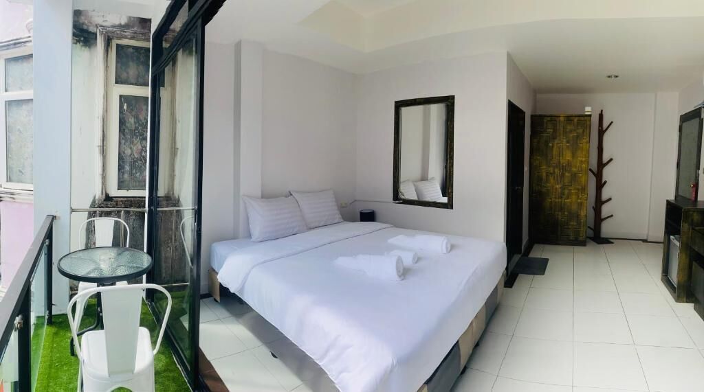 Habitación de hotel con una cama, una mesita de vidrio y una silla.