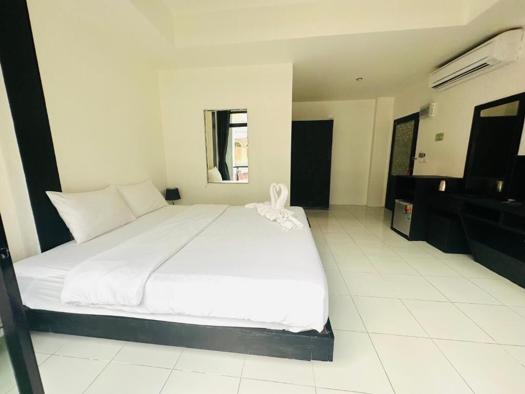 A hotel room with a large bed, a small window, a mirror, and a TV.