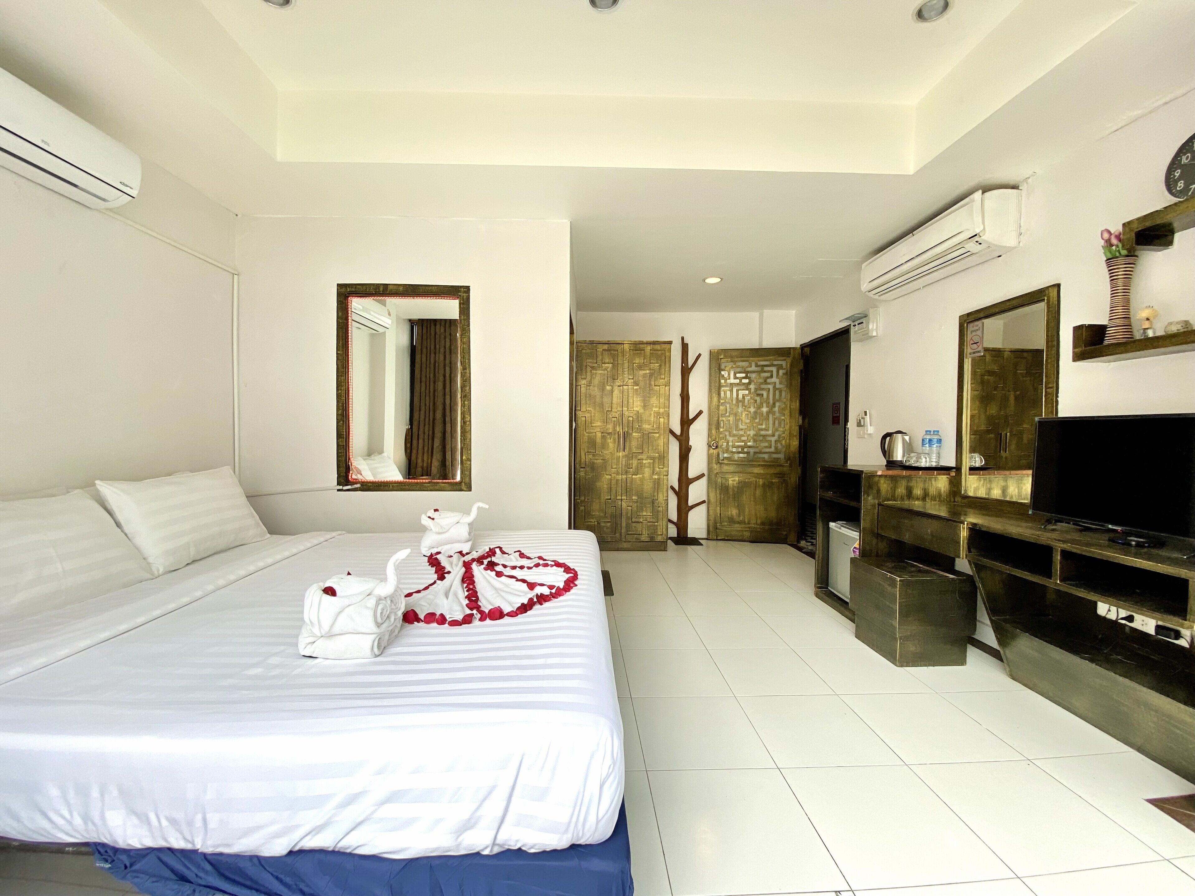 A hotel room with a bed, a TV, a mirror, and a door with a decorative pattern.