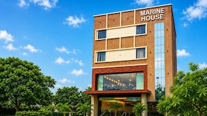 Un bâtiment moderne avec une enseigne indiquant « MARINE HOUSE » et un espace extérieur bien entretenu, agrémenté de plantes en pot.
