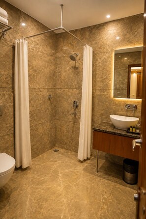 Un baño moderno con cabina de ducha, inodoro y lavabo con espejo.