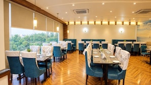 Un restaurant doté de nombreuses tables et chaises, d’un plancher en bois et de grandes fenêtres offrant une vue dégagée.