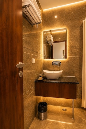 Een badkamer met een houten deur, een wastafel met een spiegel erboven en een handdoekhouder.