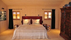 Ein Schlafzimmer mit Holzwänden, einem großen Bett, zwei Nachttischlampen und einem Schrank.