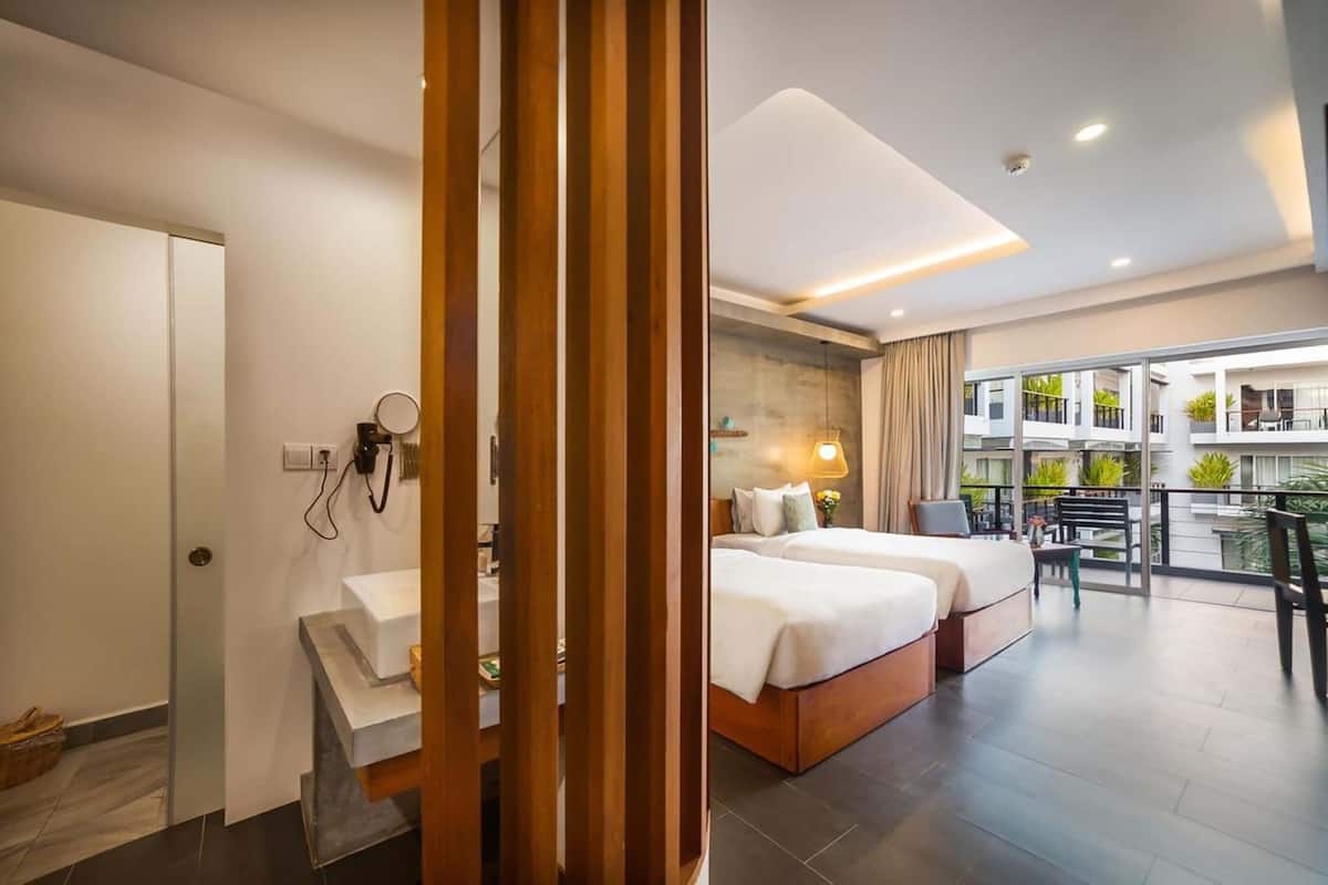 A modern hotel room with a large bed, a separate seating area, and a balcony with a view.