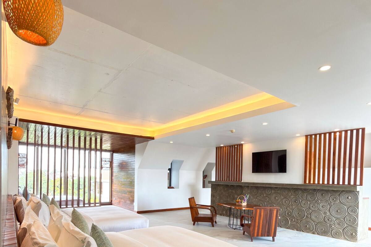 A modern bedroom with a large bed, a dining area, and a TV mounted on the wall.