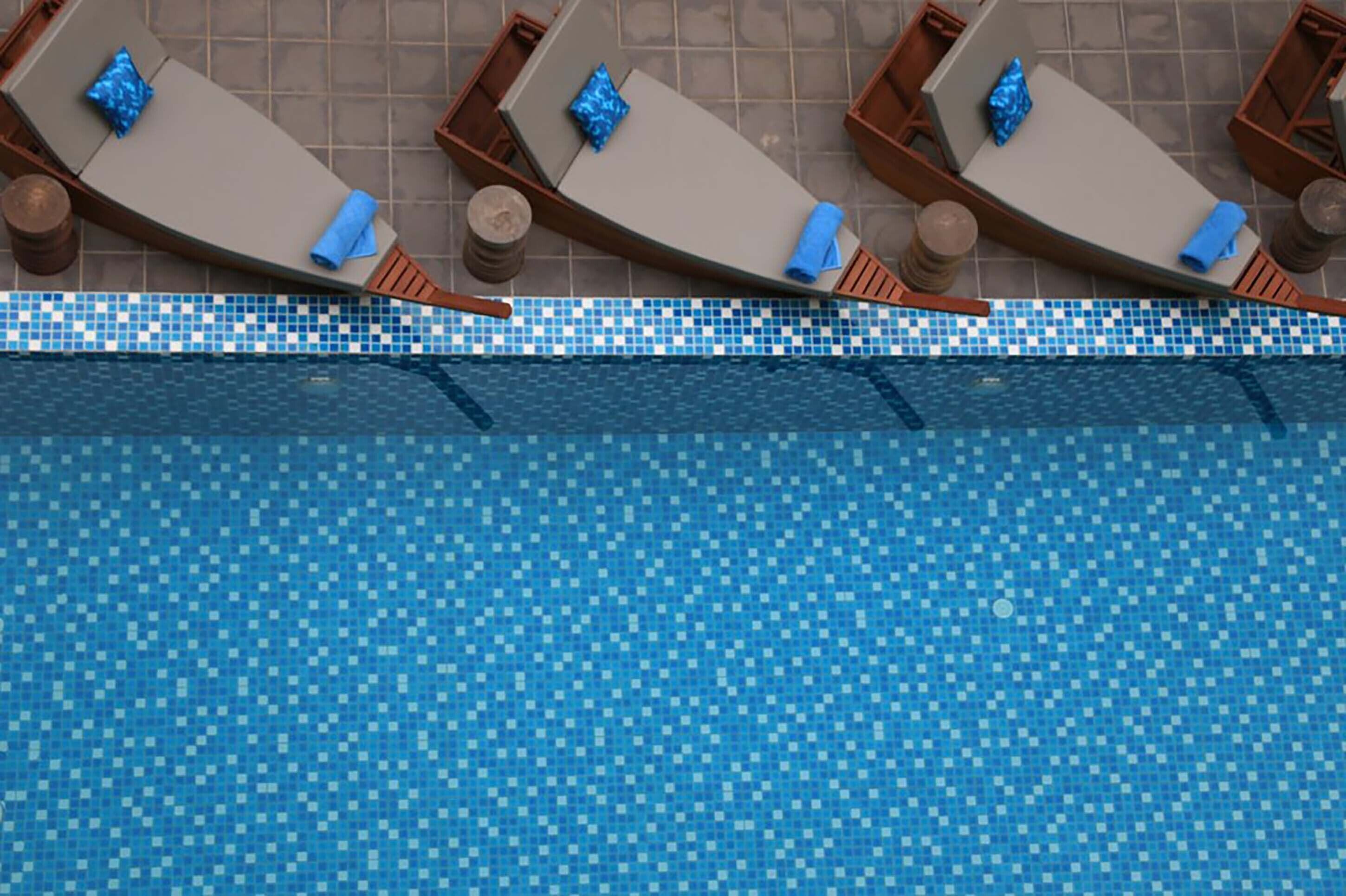 Ein Poolbereich mit Liegestühlen und einem gefliesten Pool.