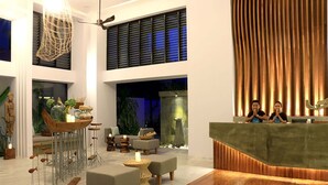 A modern lobby with a reception desk, seating area, and a large window with blinds. - Riversoul Boutique (Siem Reap)